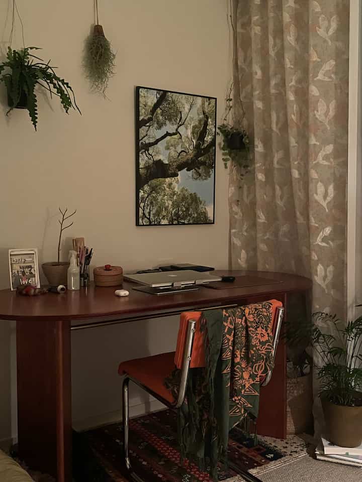 ベージュとブラウンの木目調が調和する書斎、デスクとハンギングプラントが配置されたナチュラルモダンなインテリア