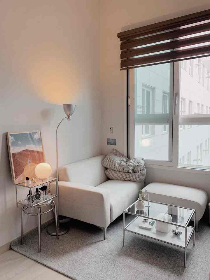 Warm white and gray toned living room featuring a Mid-Century Modern sofa and glass coffee table with cozy ambiance