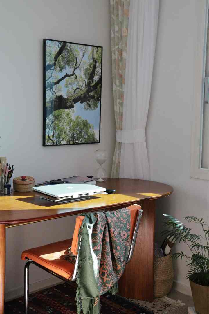 White-walled small cozy home office featuring wood tone desk and office chair with natural light