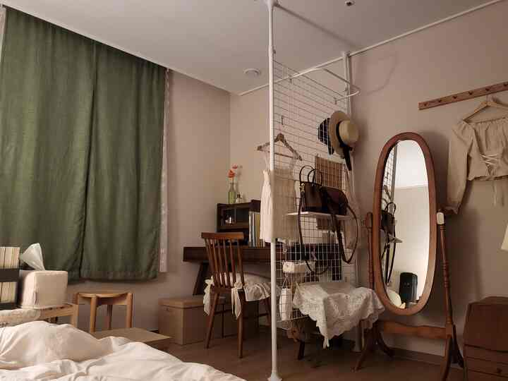 ナチュラルウッド調とヴィンテージスタイルの小さな寝室、薄いベージュの壁とグレーのカーテンが調和する温かみのある空間