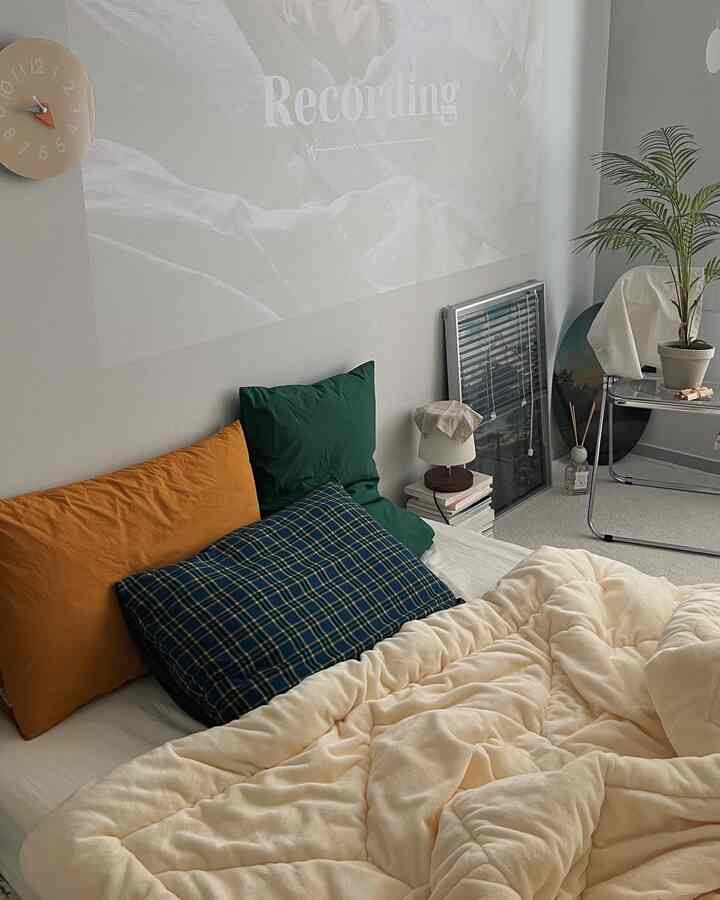 アイボリーとグリーンの色合いの寝室、枕と植物が配置されて自然な雰囲気のあるインテリア