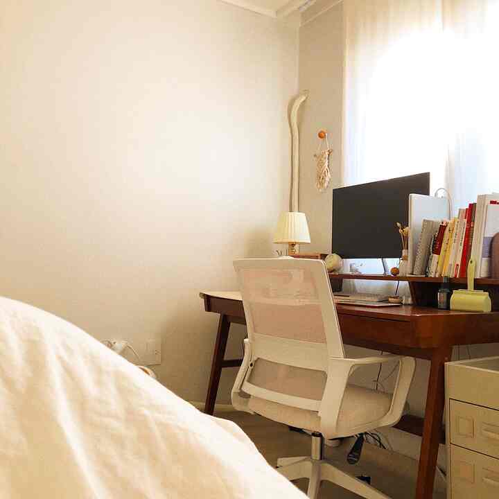 White and wood-tone walk-in closet featuring a vanity desk with office chair, creating a neat and cozy atmosphere
