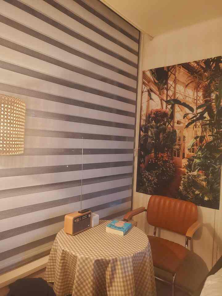 Beige and brown toned small dining room featuring a checkered tablecloth and rattan floor lamp with cozy ambiance