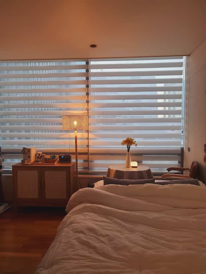 Natural style bedroom with white and wood tones, featuring a bed, floor lamp, and nightstand creating a cozy atmosphere