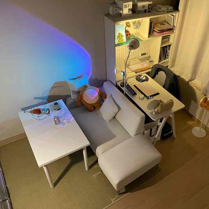 White and beige toned small home office and living area featuring a modern sofa and desk arranged in a cozy setting