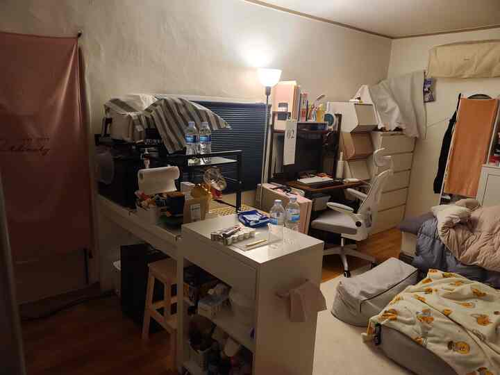 Compact bedroom in white and brown tones featuring a computer desk, office chair, and storage units with a practical atmosphere