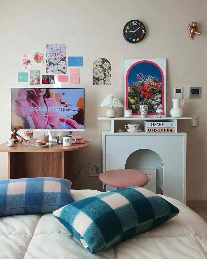 Beige-walled living room for single household featuring wood tone furniture, home cafe accessories, posters, and a pink stool creating a simple natural ambiance