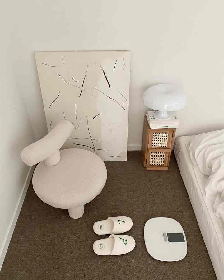 Natural modern toned bedroom with beige chair, rattan decor, and white bedding creating a simple atmosphere