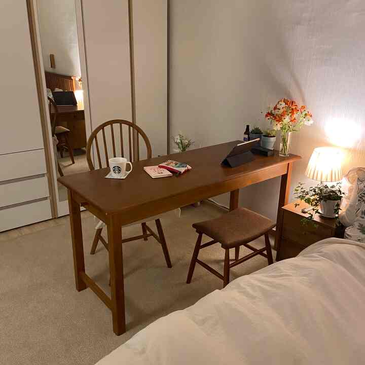 温かみのある木目調と白を基調とした寝室、木製のテーブルと椅子が配置された雰囲気のあるおうちカフェインテリア