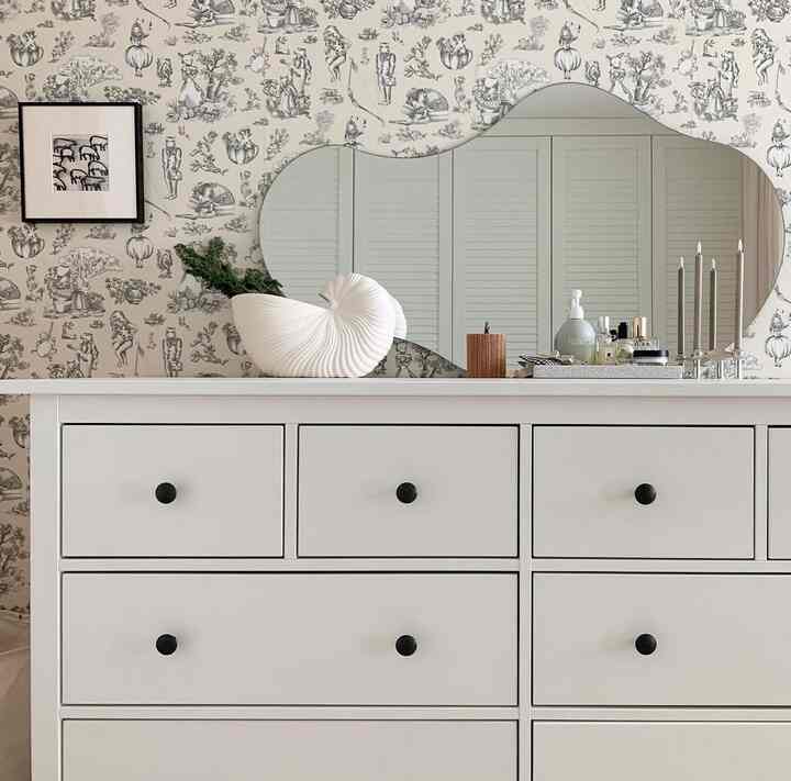 白を基調としたウォークインクローゼット、アクセント壁紙とチェストが配置された雰囲気のあるインテリア