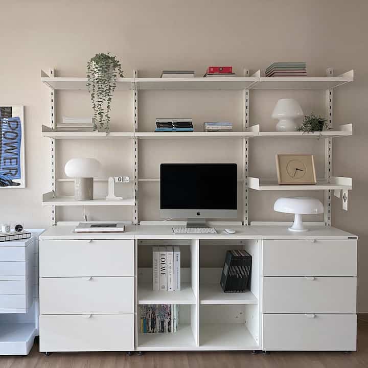 Bright white and natural toned living room home office with orderly bookshelves and shelves in a modern space