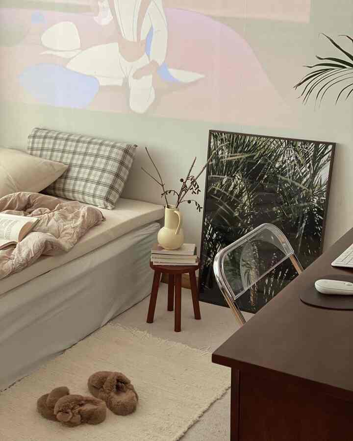 ベージュとナチュラルカラーの寝室、ベッドとサイドテーブル、ポスターが配置された雰囲気のあるインテリア