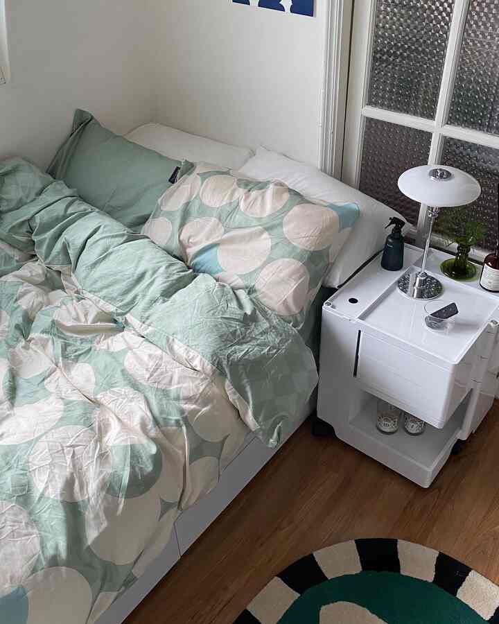 ミントと白を基調とした寝室、きれいに整えられたベッドと収納ナイトテーブルが配された落ち着いた空間