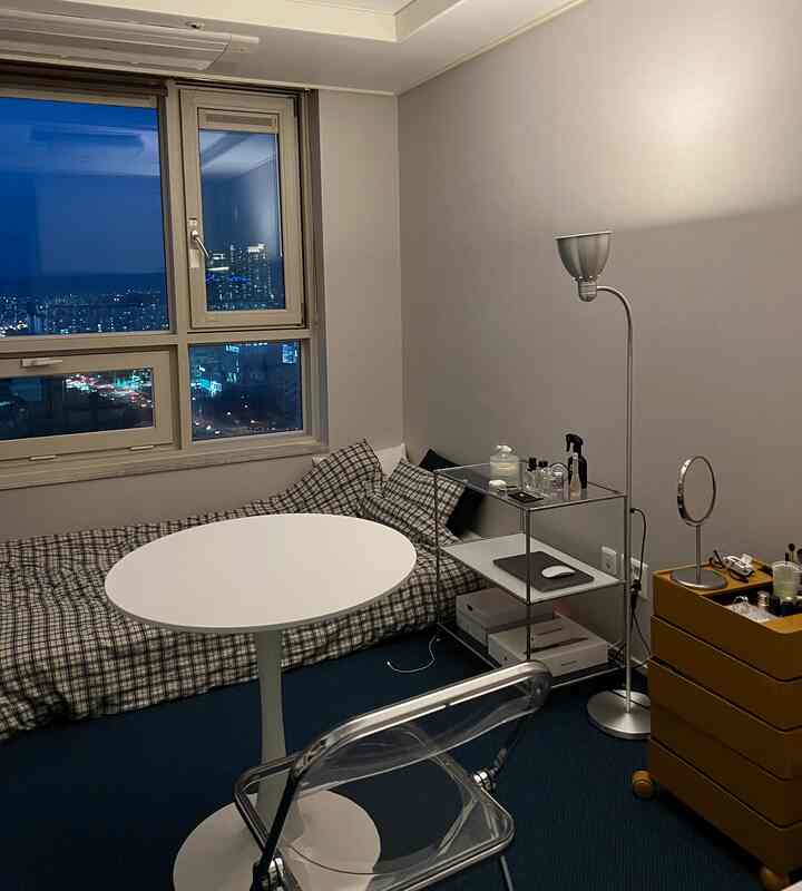 White and sky blue toned single household bedroom featuring transparent chair and round table with compact layout