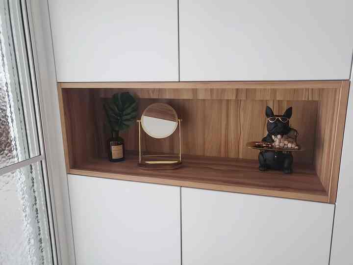 ナチュラルなトーンの埋め込み棚型靴箱の中央に、ゴールドの卓上鏡と黒い犬のオブジェが配置された清潔感のある玄関スペース