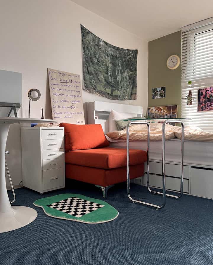 Cozy bedroom in white and navy tones featuring red sofa and metal table, showcasing a modern and compact space