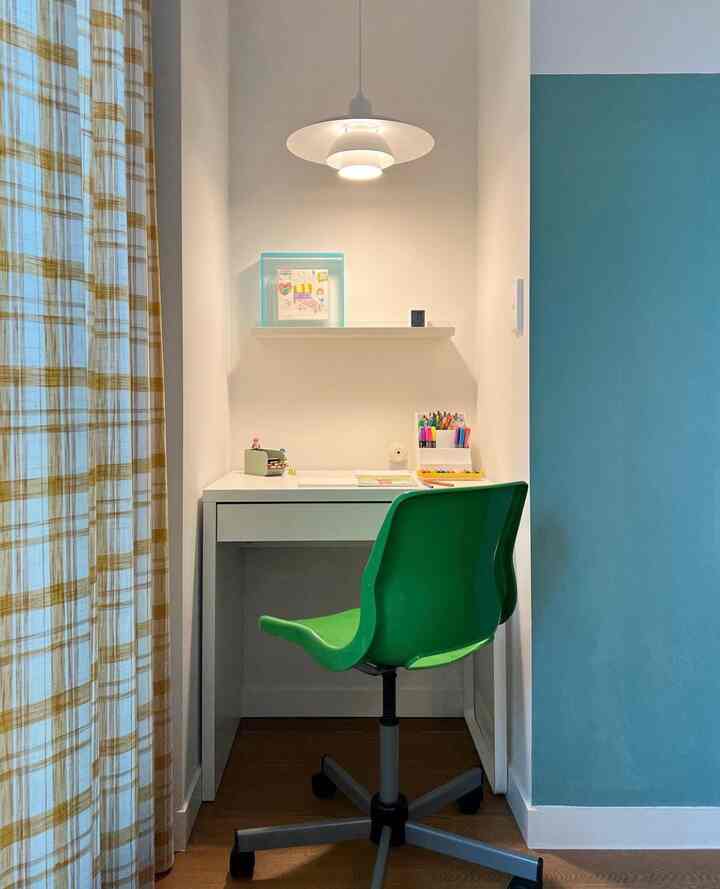 白い壁と黄色のチェックカーテンがある子供部屋、緑の椅子と白いデスクが配置された集中できる空間