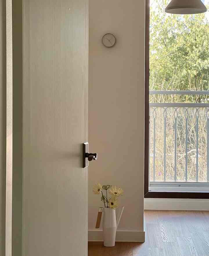 ベージュとナチュラルトーンの子供部屋の入口、花瓶と時計が配置された落ち着いた空間