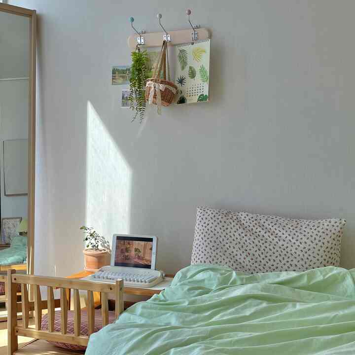 Minimal bedroom with white walls and wood-tone furniture, featuring a bed and small desk in a single household setting