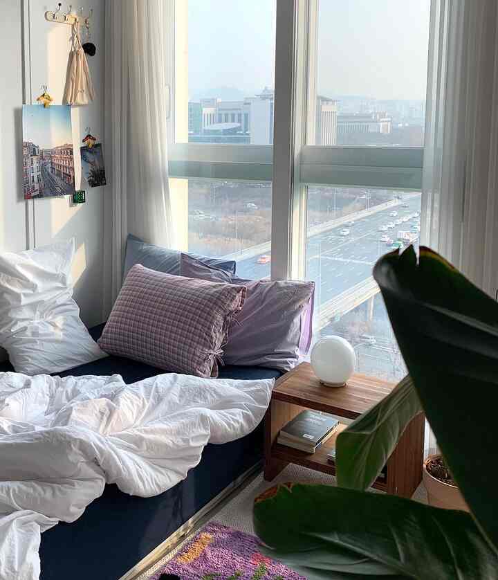 白とネイビーカラーの6畳寝室、右側に大きな窓と木製のナイトテーブルが配置された自然でモダンなインテリア