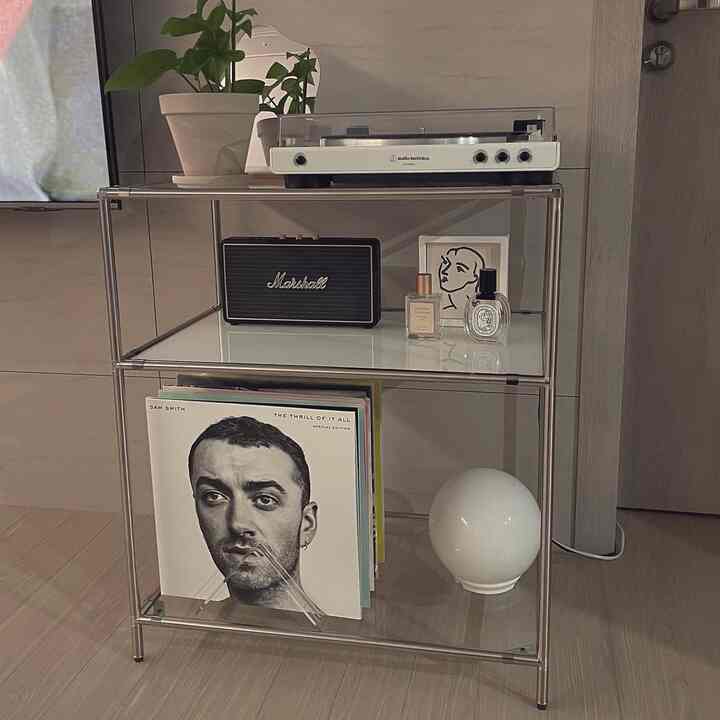 Modern space with white tones featuring a metal frame modular shelf holding an Audio-Technica turntable and a Bluetooth speaker, presenting a clean interior.