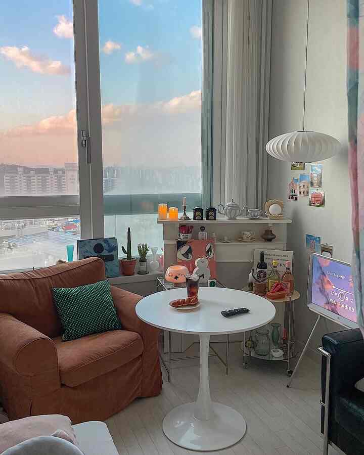 白い床と壁が特徴的なワンルームのリビング、ブラウンのソファと円形のコーヒーテーブルが温かみのある雰囲気を演出