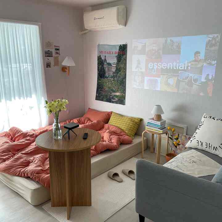 Natural-toned bedroom featuring a wooden round table and orange duvet cover in a cozy home cinema setup