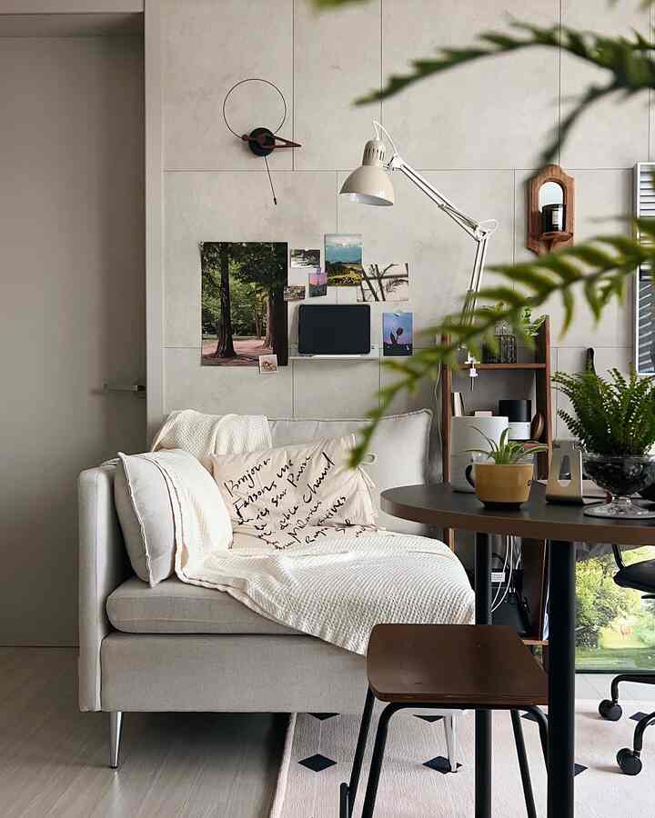Beige-toned living room featuring a sofa, rug, stool, and table lamp with cozy, natural atmosphere