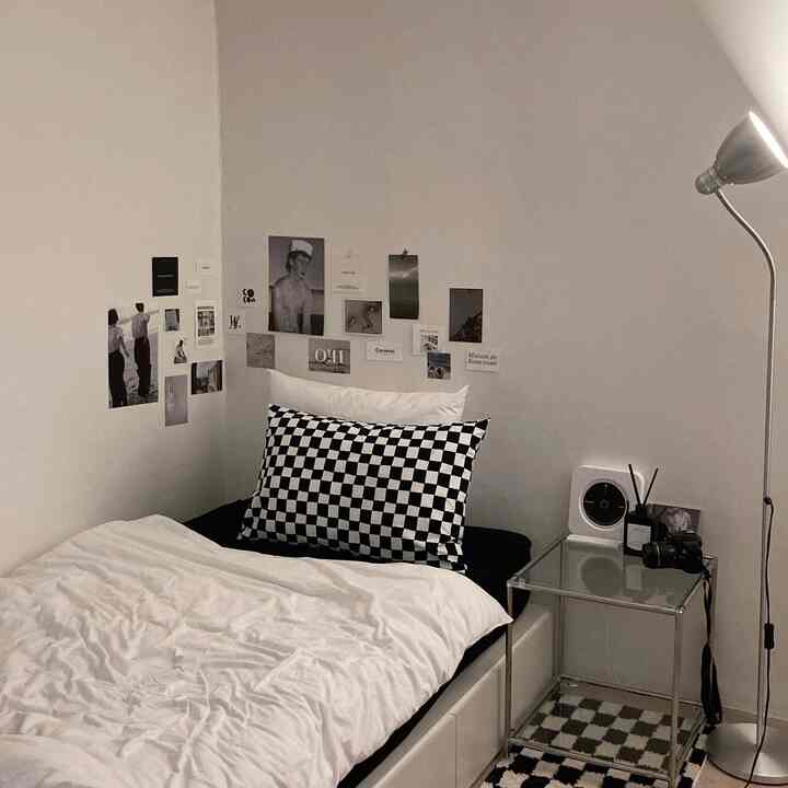 Monotone bedroom featuring a bed with checkered pillow and white bedding, decorated with black and white posters on the wall