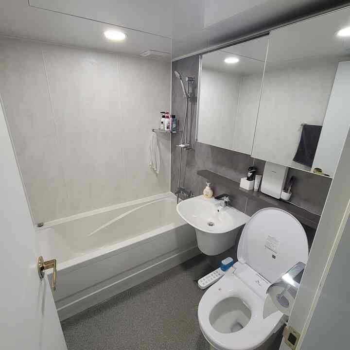 Modern bathroom in white and gray tones featuring bathtub, sink, and toilet with a clean layout
