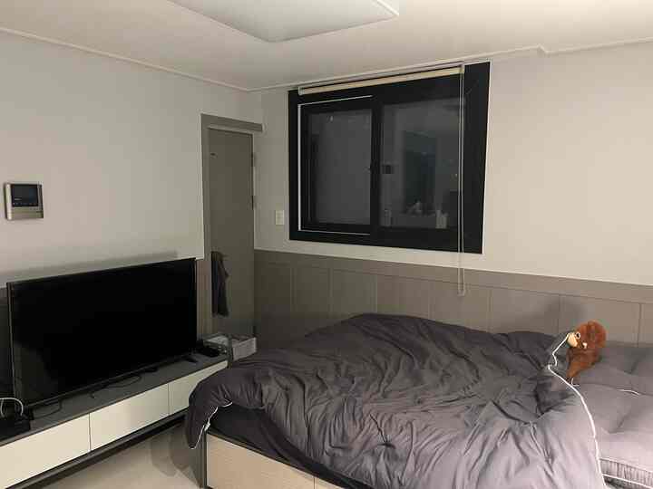 Gray and black toned bedroom featuring hotel-style bedding and a TV stand with a clean, modern atmosphere