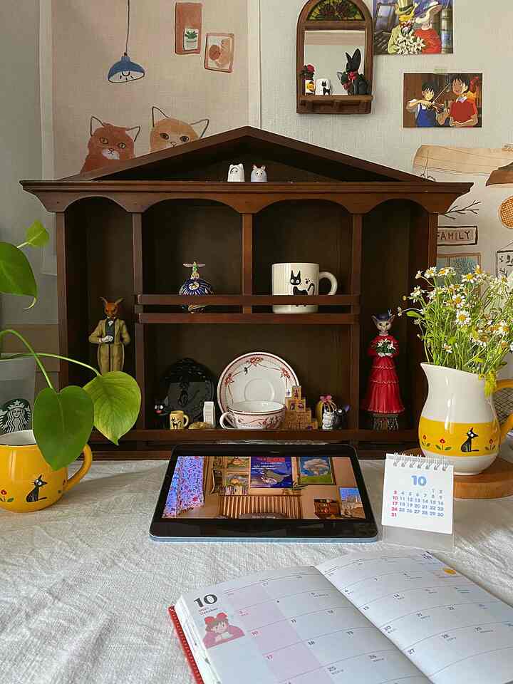 ヴィンテージ風のデスク空間、ダークウッドの棚と植物、カレンダー、タブレットが調和した雰囲気のあるインテリア