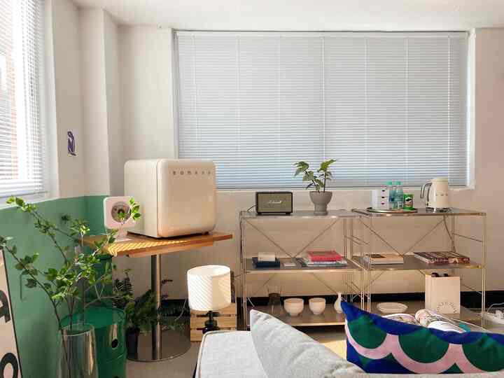 White and natural toned home office space featuring shelves, plants, and retro mini fridge with cozy atmosphere