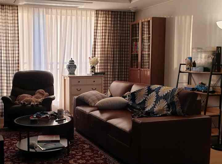 Brown and white toned living room featuring leather sofa, armchair, and coffee table in a cozy vintage style