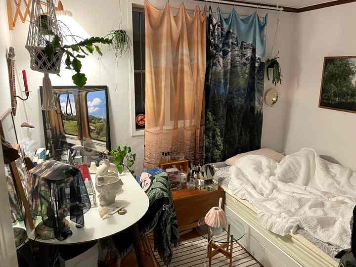 Small bedroom with dominant white and brown tones featuring natural furniture, curtains, and plant decorations, creating a cozy atmosphere