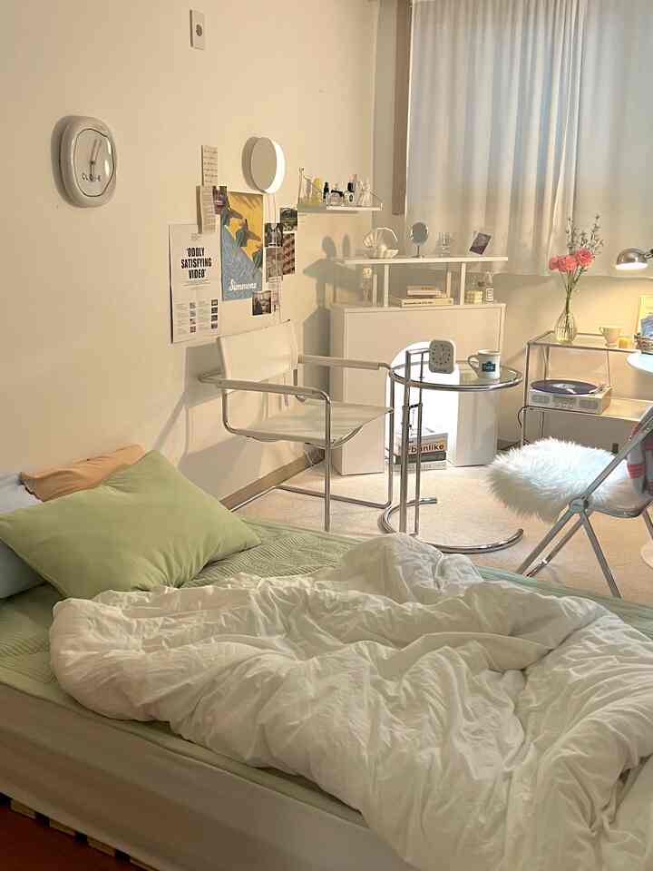 白と緑のトーンの寝室、ベッドとカーテン、モダンな椅子が配置された落ち着いた雰囲気のインテリア