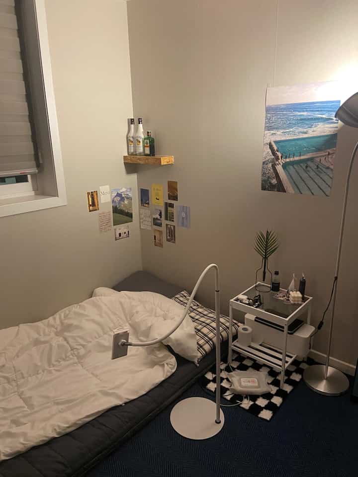 White and gray toned small single bedroom featuring minimal nightstand and floor lamp with calm atmosphere