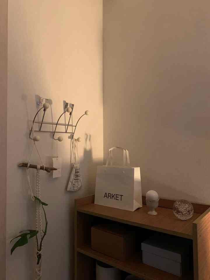 暖かみのあるブラウンとホワイトの玄関、コートハンガーとガーランド、オブジェが配置された雰囲気のあるインテリア