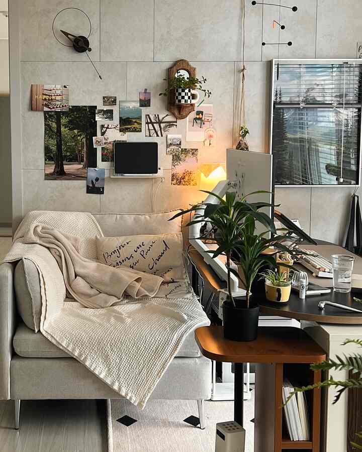ベージュとナチュラルトーンのリビング兼ホームオフィス、快適なソファと植物、モニターアームのデスクが調和した雰囲気のあるインテリア