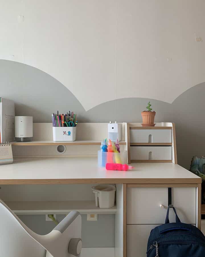 White and natural wood-tone kids' room featuring a desk with drawers and a painted wall for a clean study space