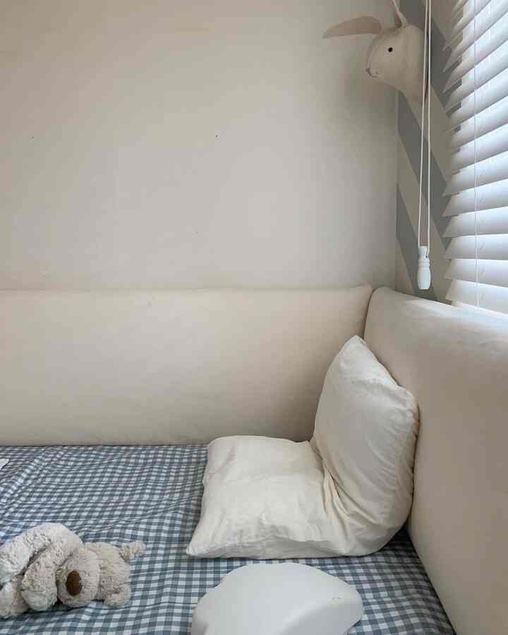 ベージュ色調の子供部屋、クッションパディングとチェック柄の寝具が配置された暖かみのあるインテリア