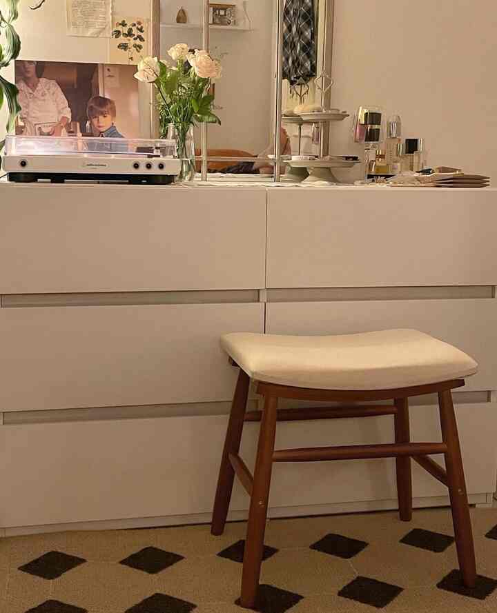 A cozy multi-purpose space with white furniture, brown wooden stool, and vintage accessories