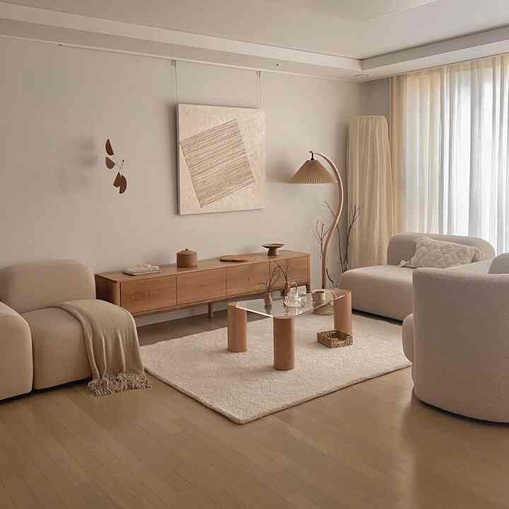 A modern living room with natural wood tones and ivory hues, featuring sectional sofas and a rug creating a cozy atmosphere