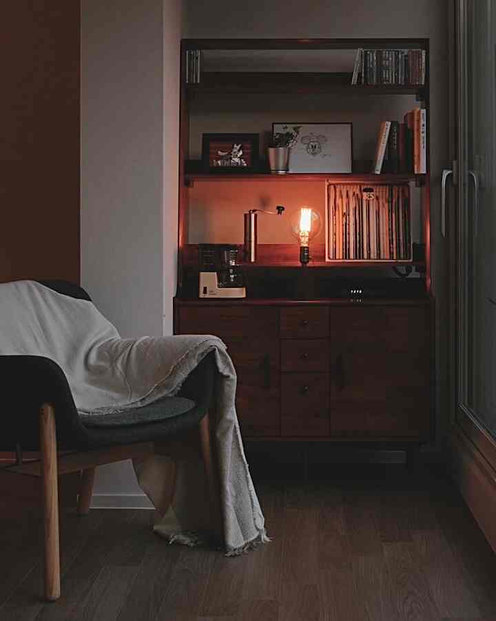 Cozy small living room in natural color tones featuring wooden cabinet, armchair, and warm accent lighting