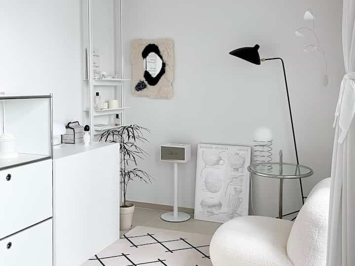 Modern living room in white and natural tones featuring a rounded sofa and glass side table creating a cozy atmosphere