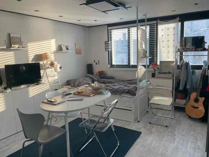 ナチュラルなトーンのワンルーム、白い家具とグレーの寝具が配置された落ち着いた雰囲気のインテリア