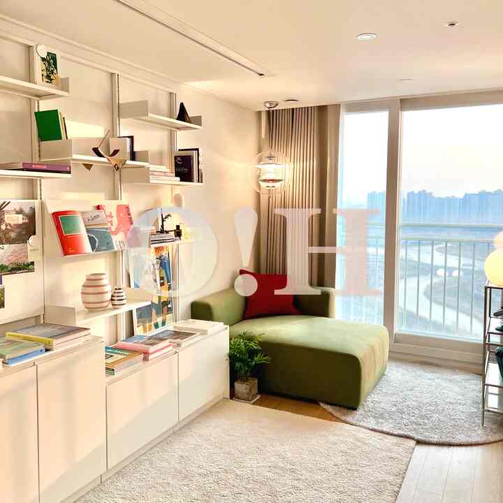 White-toned living room featuring a green sofa and bookshelf with a natural, cozy atmosphere