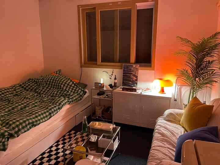 Compact single household bedroom with white furniture and orange lighting, featuring mid-century modern and retro ambiance