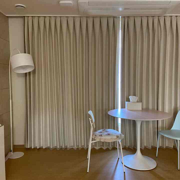 ベージュと白のトーンの小さなワンルーム、丸いダイニングテーブルと椅子が配置された雰囲気のあるおうちカフェ空間