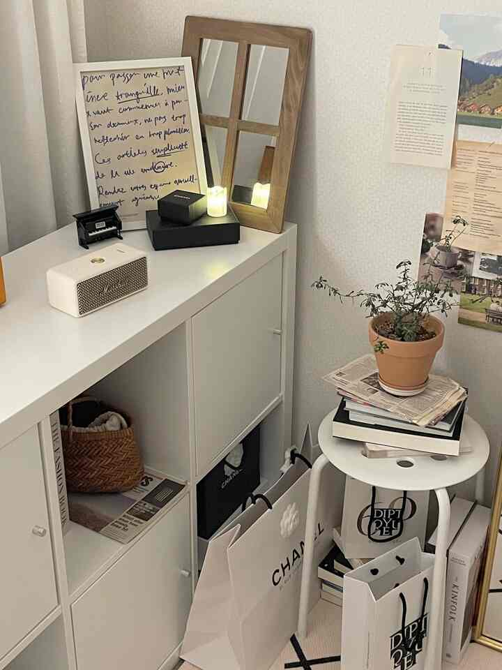 Natural-toned small space featuring white storage cabinet and stool, decorated with plants, mirror, and cozy accessories